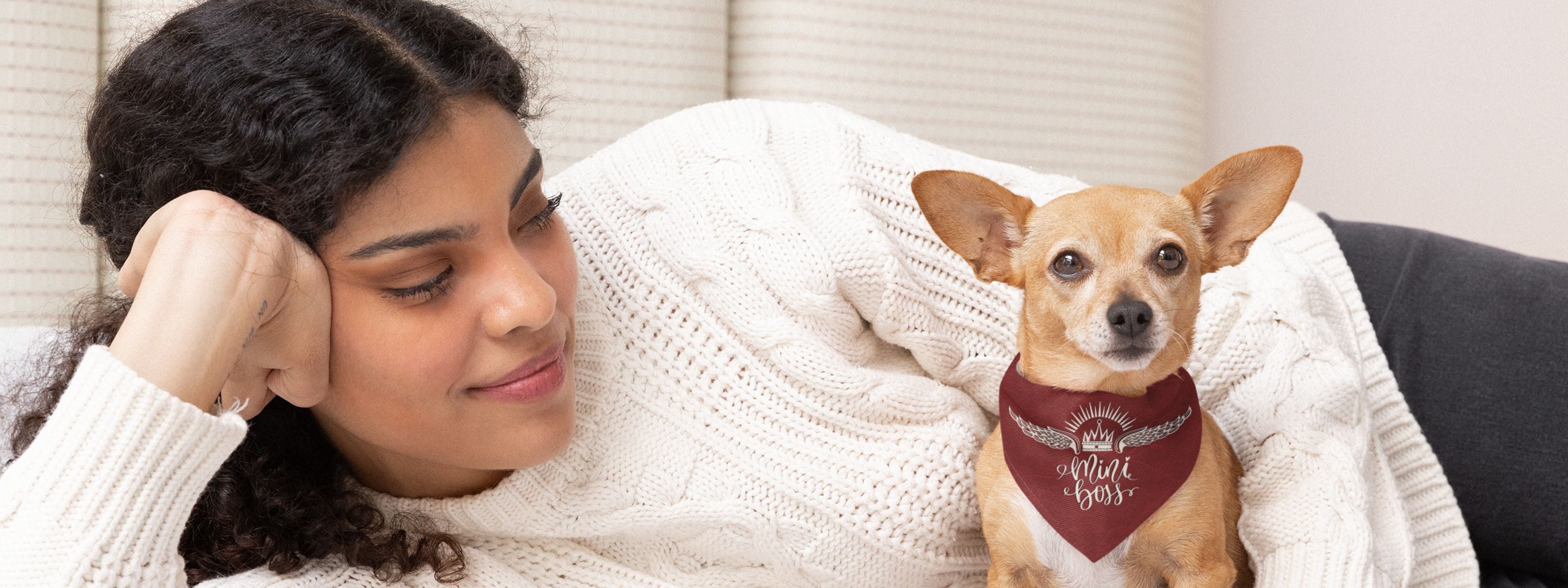 Woman lying down next to cute dog wearing red graphic bandana saying Mini Boss.